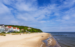 Blick auf den Strand in Bansin auf der Insel Usedom mit der Ostsee und Wohnhäusern im Hintergrund.