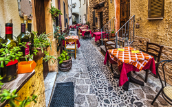 Enge Gasse mit Tischen und Stühlen vor einem Restaurant.