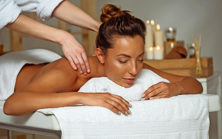 Junges attraktives Mädchen, welches die Massage sich entspannt im Badekurortsalon hat.