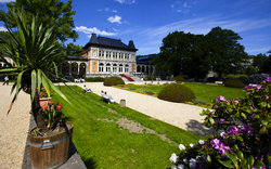 Historisches Gebäude mit Gartenanlage, Blumen und blauen Himmel.