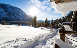 Winterlandschaft in Ruhpolding mit Sonne, verschneiten Bergen und Hütten.