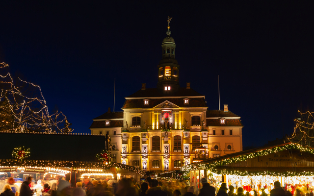 Weihnachtsmarkt vor dem beleuchteten historischen Rathaus in Lüneburg während des Winters.