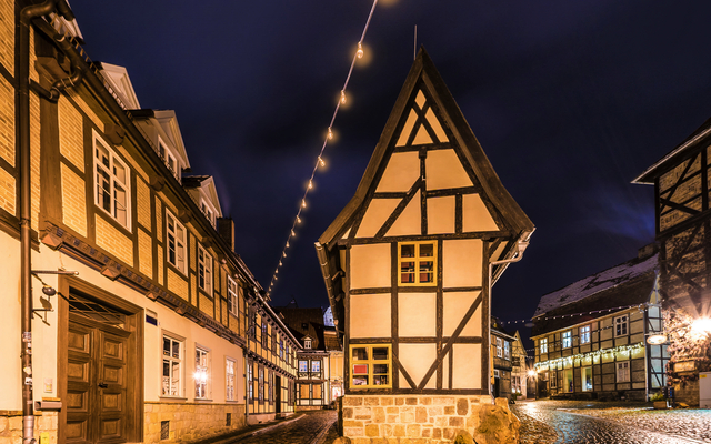 Fachwerkhaus in einer beleuchteten Altstadt bei Nacht.