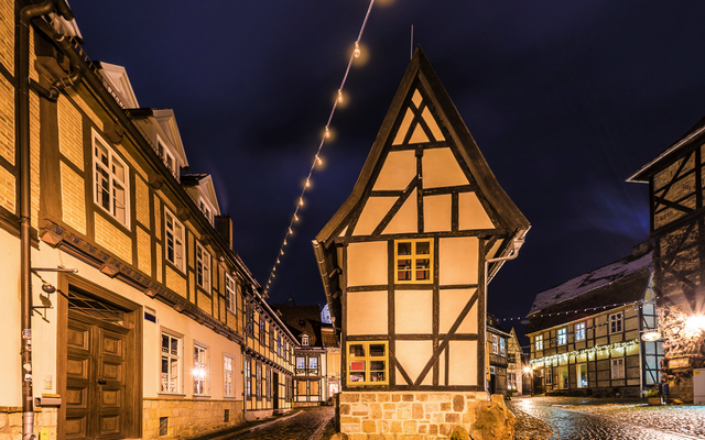Fachwerkhaus in einer beleuchteten Altstadt bei Nacht.