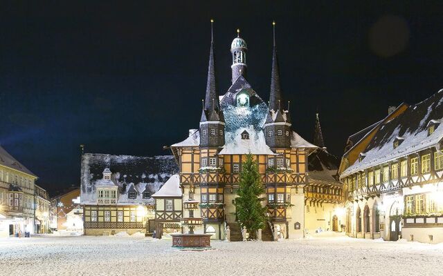 Verschneiter Marktplatz mit Fachwerkhäusern bei Nacht.