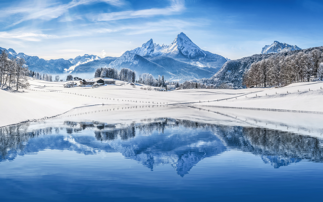 Verschneite Berglandschaft mit Spiegelung im ruhigen See.