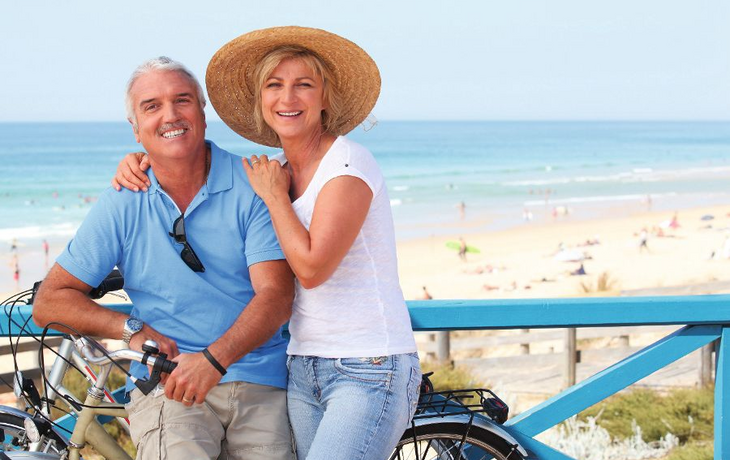 Mature couple with bikes by the beach