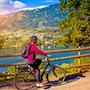 Frau mit E-Bike Radfahren neben einem schönen See-See und Fahrrad