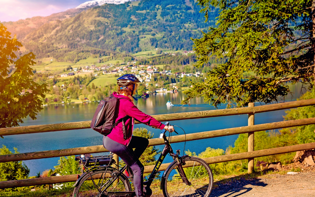 Frau auf Fahrrad mit Berg- und Seelandschaft im Hintergrund