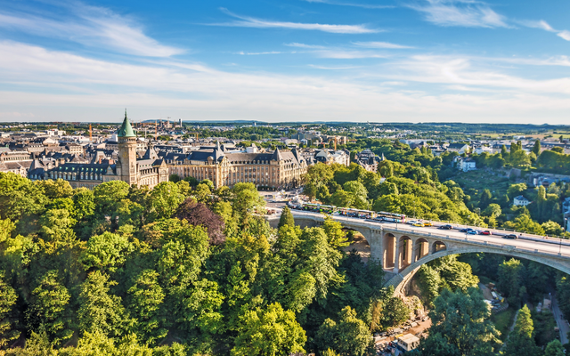 Stadtansicht mit Brücke und historischer Architektur, umgeben von Bäumen.