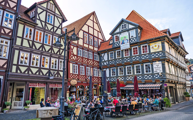 Fachwerkhäuser mit Restaurants und Menschen in einem belebten Straßencafé.