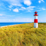 Ellenbogen Leuchtturm auf Sanddüne gegen blauen Himmel mit weißen Wolken an der Nordküste der Insel Sylt, Deutschland