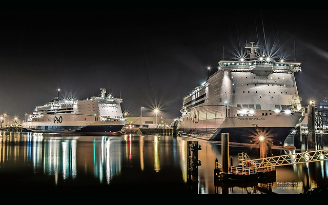 Zwei große Kreuzfahrtschiffe im Hafen bei Nacht.