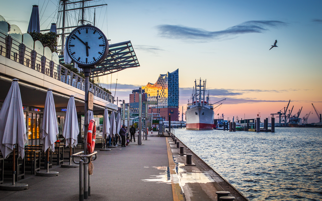 Hafenpromenade bei Sonnenuntergang mit Schiff und Elbphilharmonie im Hintergrund.