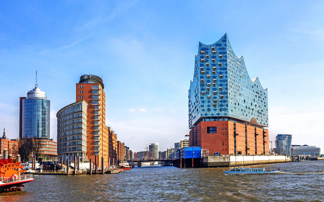 Elbphilharmonie in Hamburg mit umliegenden modernen Gebäuden am Wasser bei klarem Himmel.