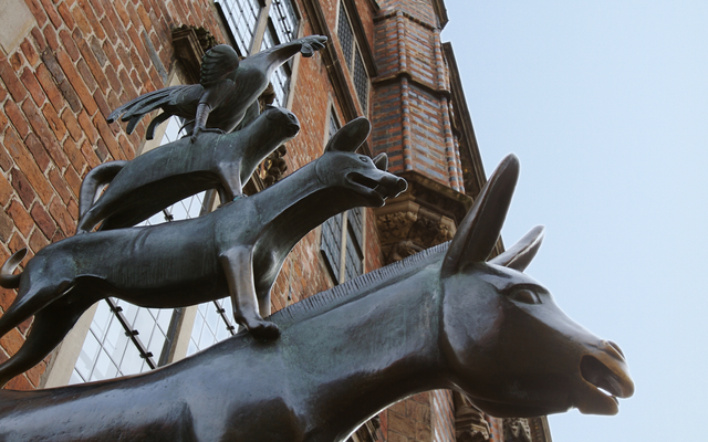 Skulptur der Bremer Stadtmusikanten vor einem roten Backsteingebäude.