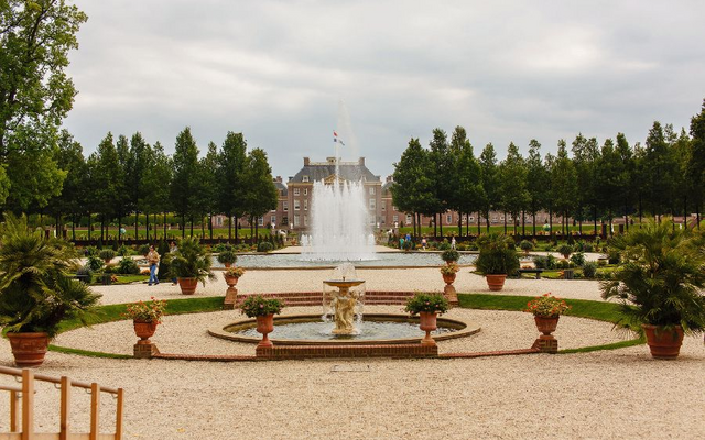 Schlossgarten mit Brunnen und Bäumen im Hintergrund