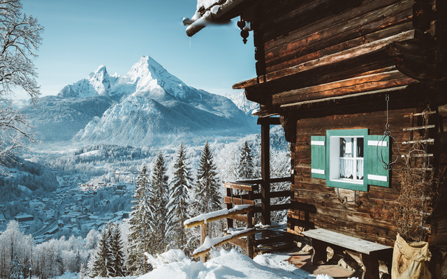 Winterliches Bergpanorama mit Holzhütte und schneebedeckten Bäumen.