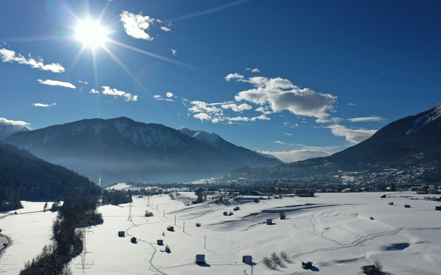Verschneite Landschaft mit Bergen und strahlendem Sonnenschein.