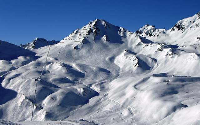 Schneebedeckte Berglandschaft unter klarem blauen Himmel.