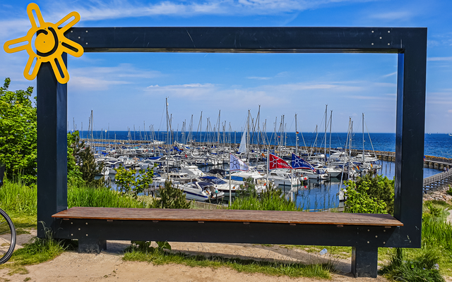 Ein großer Bilderrahmen mit Blick auf einen Yachthafen und das Meer im Hintergrund.