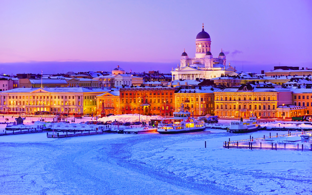 Verschneite Winterlandschaft mit beleuchteter Stadt und Dom im Hintergrund.
