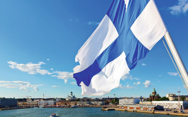 Finnische Flagge weht über Helsinki mit Stadtansicht im Hintergrund