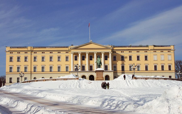 Schloss in Oslo mit Statue im Vordergrund und Schnee bedeckt.
