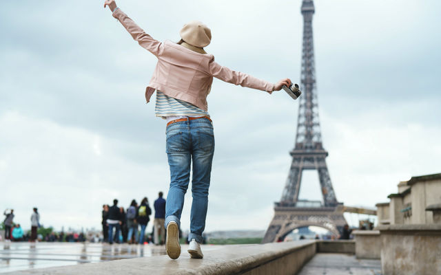 Person springt vor dem Eiffelturm in Paris.