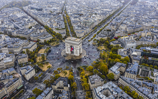 Luftaufnahme des Arc de Triomphe in Paris, umgeben von Straßen und Gebäuden.