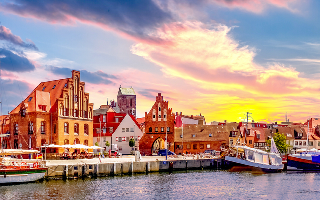 Historische Hafenstadt mit Segelbooten bei Sonnenuntergang.