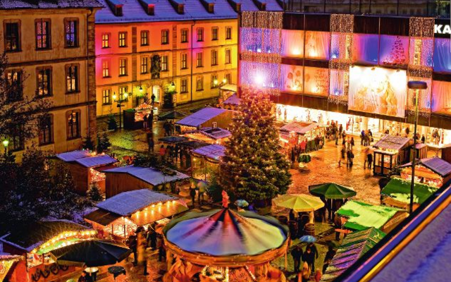 Beleuchteter Weihnachtsmarkt in Fulda bei Nacht mit geschmücktem Baum und Karussell.