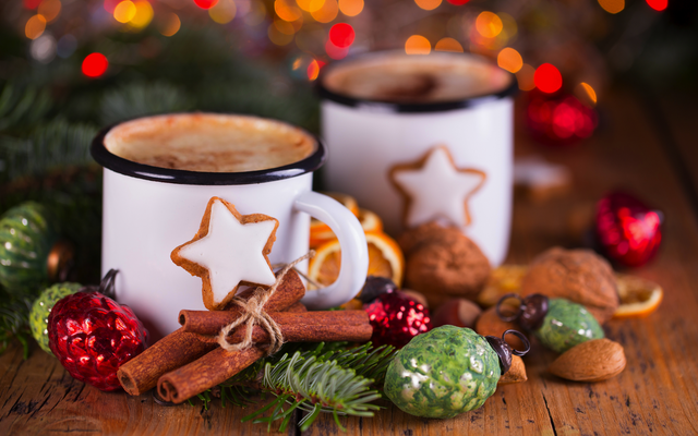 Zwei Becher mit Kakao, Lebkuchen und Weihnachtsdekoration auf Holztisch.