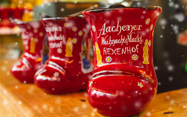 Rote Stiefeltassen vom Aachener Weihnachtsmarkt auf einem Holztisch.