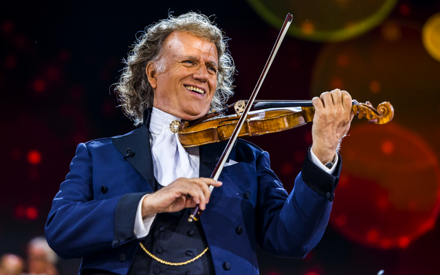 Ein Geiger spielt die Geige auf einem Konzert, möglicherweise Andre Rieu auf einer Bühne.