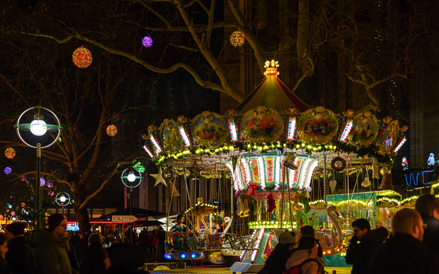 Beleuchtetes Karussell auf einem Weihnachtsmarkt bei Nacht.