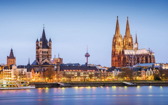 Kölner Skyline bei Dämmerung, mit dem Dom und Rhein im Vordergrund.