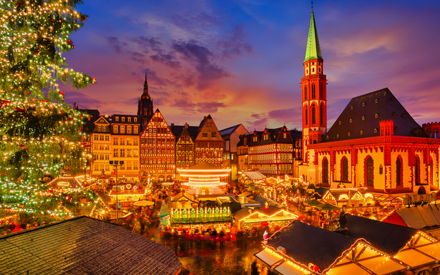 Weihnachtsmarkt am Abend mit Beleuchtung und Kirchturm im Hintergrund