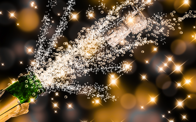 Champagnerflasche mit spritzendem Korken und Schaumemission vor unscharfem Hintergrund