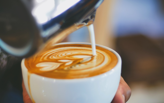 Nahaufnahme eines Latte Macchiato mit Latte Art in einer weißen Tasse.