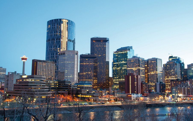 Skyline einer modernen Stadt mit beleuchteten Hochhäusern bei Abenddämmerung.