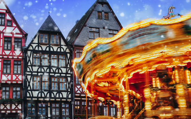 Fachwerkhäuser mit Weihnachtskarussell und Schneefall.