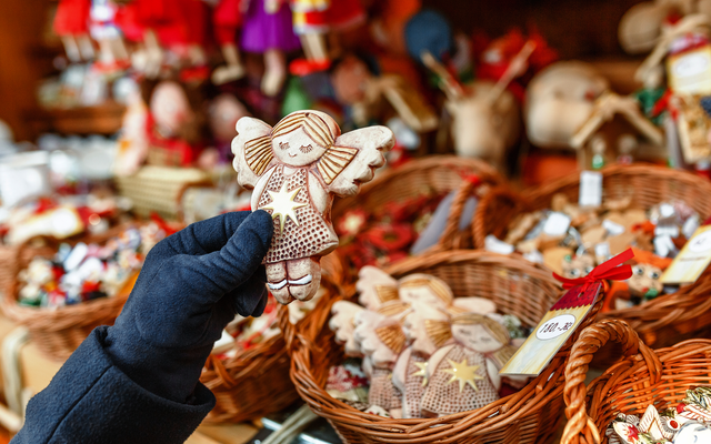 Handgemachter Weihnachtsengel auf einem festlich dekorierten Weihnachtsmarkt im Winter.
