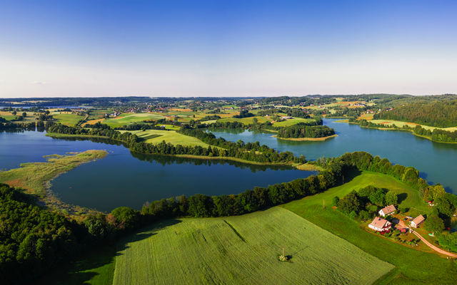 Luftaufnahme einer grünen Landschaft mit Seen und bewaldeten Gebieten.