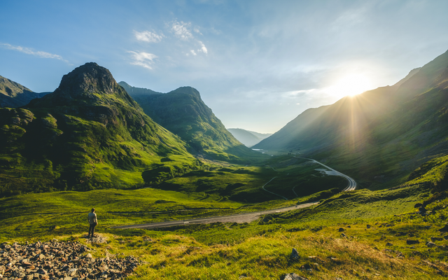Weite grüne Täler und Berge unter blauem Himmel im Sonnenlicht