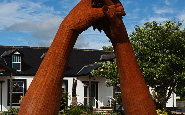Große hölzerne Skulptur von zwei Händen vor einem Gebäude.