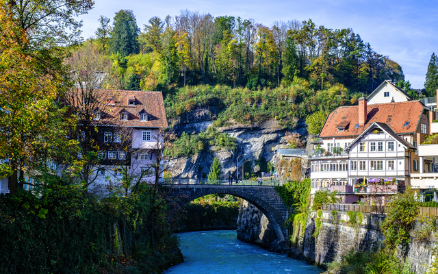 Malerische Flusslandschaft mit Häusern und Brücke im Herbst.