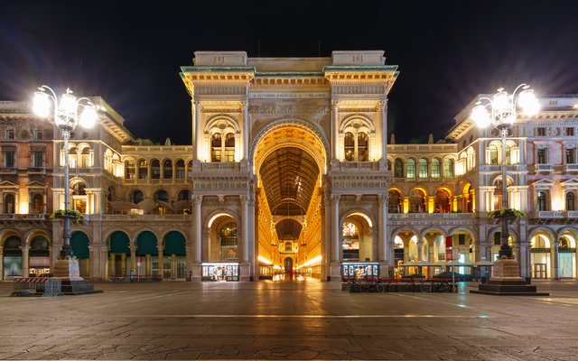 Historisches Gebäude bei Nacht mit beleuchtetem Torbogen.