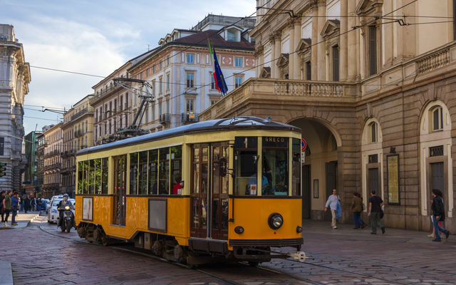 Straßenbahn in einer städtischen europäischen Straße mit Gebäuden im Hintergrund.