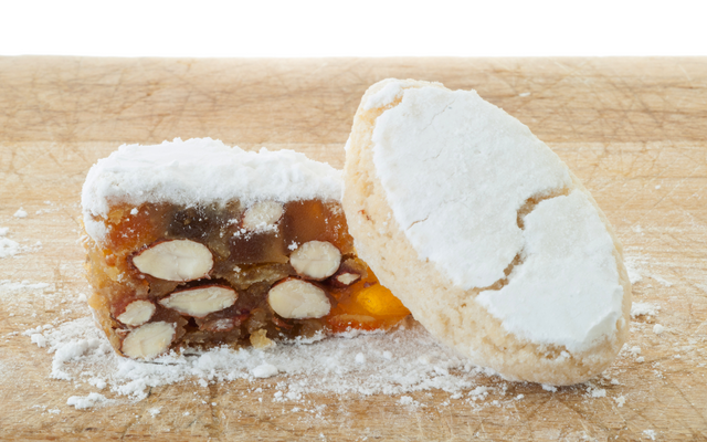 Zwei Stücke Panforte-Gebäck auf einem Holzbrett.